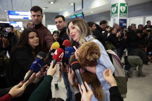 epa12831005 A Greek citizen speaks to the media as she arrives with her dog after being repatriated on a flight from Abu Dhabi organized by the Greek Ministry of Foreign Affairs at Eleftherios Venizelos Airport in Athens, Greece, 18 March 2026. About 100 Greek nationals were repatriated under the Greek Ministry of Foreign Affairs' special 'Kivotos'...