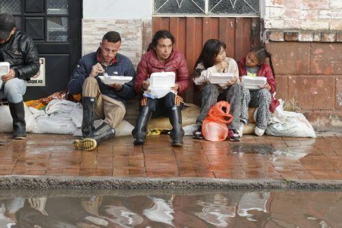 epa12834950 People eat food in front of a street flooded by heavy rains in Facatativa, Colombia, 19 March 2026. According to the mayor of Facatativa, Luis Carlos Casas, and local emergency agencies, heavy rains caused the Mancilla and San Rafael creeks to overflow and feed the Botello River, leading to severe flooding that affected more than 2,000 families....