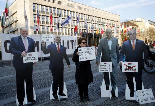 epa12837177 A woman poses with cut outs of Hungarian Prime Minister Viktor Orban, USA President Donald Trump, Israelian Prime Minister Benjamin Netanyahu and former Slovenian Prime Minister and leader of the Slovenian Democratic party (SDS) Janez Jansa outside the American Embassy in downtown Ljubljana, Slovenia, 20 March 2026. The 22 March 2026...