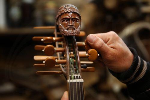 epa12838008 Hercules Bras tunes a handmade, custom-built violin featuring a carved figure of the god Poseidon on the headstock, in his father Nikolas’s workshop, where handmade stringed instruments have been crafted for 40 years, in Athens, Greece, 09 March 2026 (issued 21 March 2026). The customized shape of these hand-crafted instruments, their...