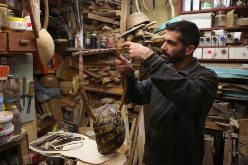 epa12838012 Hercules Bras carves the holes in order to install the tuning pegs on a lyre still in progress, in his father’s workshop, where handmade stringed instruments have been crafted for 40 years, in Athens, Greece, 26 February 2026 (issued 21 March 2026). The Bras family workshop, besides violin-family instruments, specializes also in making...