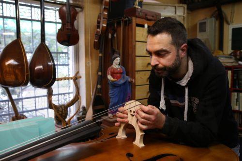 epa12838017 Socrates Bras sets up the bridge on a handmade double bass, in his father Nikolas’s workshop, where handmade stringed instruments have been crafted for 40 years, in Athens, Greece, 26 February 2026 (issued 21 March 2026). The customized shape of these hand-crafted instruments, their construction materials, the unique timbre they produce, and the...