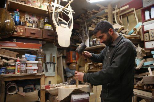 epa12838018 Hercules Bras carves the bowl (soundbox) of a lyre, in his father Nikolas’s workshop, where handmade stringed instruments have been crafted for 40 years, in Athens, Greece, 26 February 2026 (issued 21 March 2026). The customized shape of these hand-crafted instruments, their construction materials, the unique timbre they produce, and the...