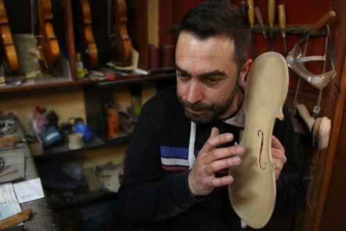 epa12838023 Socrates Bras checks the tonality of the soundboard (top) of a violin near completion, in his father Nikolas’s workshop, where handmade stringed instruments have been crafted for 40 years, in Athens, Greece, 26 February 2026 (issued 21 March 2026). The Bras family workshop, besides violin-family instruments, specializes also in making...