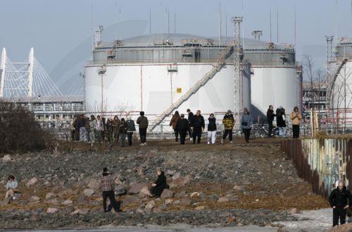 epa12841561 People walk on the shore of the Gulf of Finland with the St. Petersburg Oil Terminal in the background on a sunny day in St. Petersburg, Russia, 22 March 2026. Temperatures in St. Petersburg, Russia's second largest city, reached eleven degrees Celsius.  EPA/ANATOLY MALTSEV
