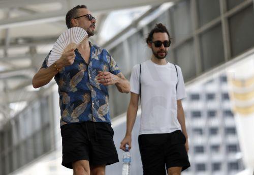 epa12859927 A foreign tourist cools off with a hand fan next to another tourist during hot weather in Bangkok, Thailand, 30 March 2026. The Meteorological Department reports that Thailand is experiencing extreme heat and urges the public to avoid outdoor activity while the Digital Economy and Society Ministry warns the country's heat index is forecasted to...