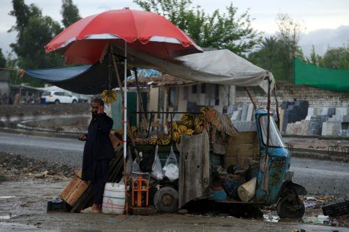 epa12860020 A vendor takes shelter under a waterproof plastic sheet during a rainy day in Peshawar, Pakistan, 30 March 2026. At least nine people were killed and several others injured after heavy rains and strong winds caused roof collapses in parts of Khyber Pakhtunkhwa and Punjab, with Bannu among the worst affected. Rescue efforts are ongoing, and...