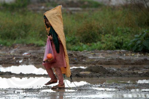 epa12860021 A girl covers herself with a plastic sacks during a rainy day in Peshawar, Pakistan, 30 March 2026. At least nine people were killed and several others injured after heavy rains and strong winds caused roof collapses in parts of Khyber Pakhtunkhwa and Punjab, with Bannu among the worst affected. Rescue efforts are ongoing, and authorities have...