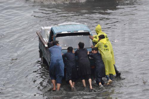 epa12866245 People push a vehicle along a flooded road following heavy rainfall in Karachi, Pakistan, 02 April 2026. Heavy rain lashed Karachi and surrounding areas, prompting local authorities to declare an emergency as a westerly weather system brought intermittent showers, strong winds, and isolated heavy downpours across the city.  EPA/SHAHZAIB AKBER
