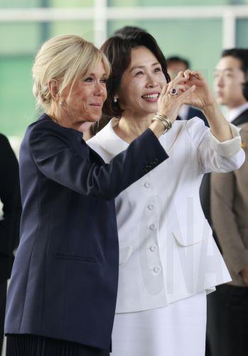 epa12866791 Kim Hea Kyung (R), wife of South Korean President Lee Jae Myung, and Brigitte Macron (L), wife of French President Emmanuel Macron, form the shape of a heart with their hands toward visitors as they tour the National Museum of Korea in Seoul, South Korea, 03 April 2026.  EPA/YONHAP / POOL SOUTH KOREA OUT