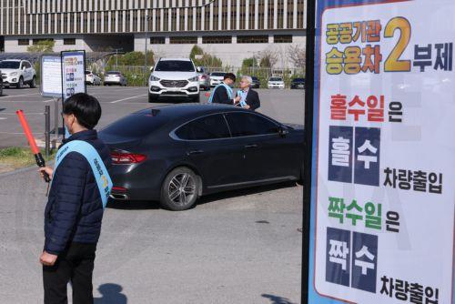 epa12874305 An employee controls the entry of vehicles at an outdoor parking lot of the government complex in Sejong, South Korea, 08 April 2026, as the government launched a two-day vehicle rotation system in the public sector that allows only cars with even-numbered plates to be driven for the day. The move is part of the government's efforts to curb...