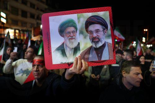 epa12874352 An Iranian holds pictures of late Iranian Supreme Leader Ayatollah Ali Khamenei and his son, current Supreme Leader Ayatollah Mojtaba Khamenei, during a demonstration following the announcement of a two-week ceasefire at Enghelab Square in Tehran, Iran, 08 April 2026. Iran and the USA agreed to the two-week truce to halt military operations and...