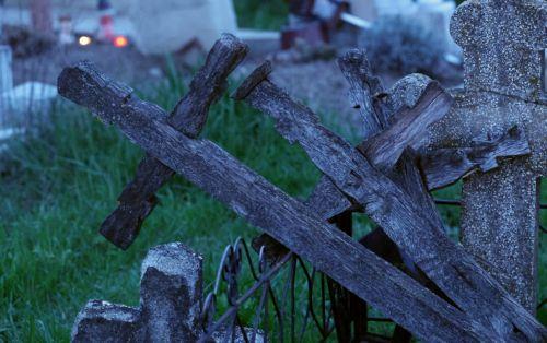 epa12876910 Old wooden crosses lie beside a grave in the village cemetery during the Orthodox Maundy Thursday memorial for the departed at a cemetery in Copaciu, Romania, 09 April 2026. Orthodox believers in the village traditionally gather in the early morning to light fires, sprinkle water and smoke over family graves, and share food in memory of their...