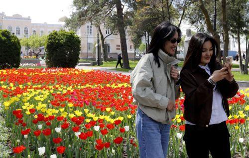epa12879878 People take a selfie in front of tulips blooming in downtown Bishkek, Kyrgyzstan, 10 April 2026.  EPA/IGOR KOVALENKO