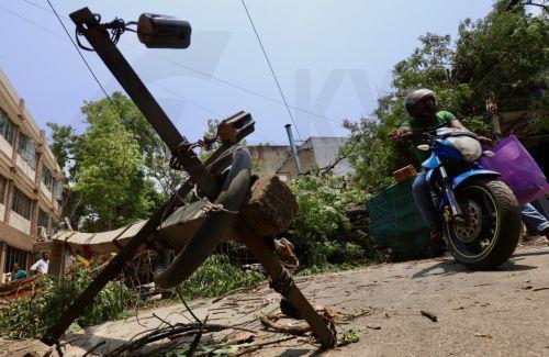 epa12923715 A motorcyclist passes by uprooted trees and broken branches following heavy overnight rain in Bangalore, India, 30 April 2026. The city was affected by over 111.5 mm of rainfall and strong winds on 29 April. More than 170 trees were uprooted, and many branches were broken due to lightning and thunderstorms. At least 10 people lost their lives in...