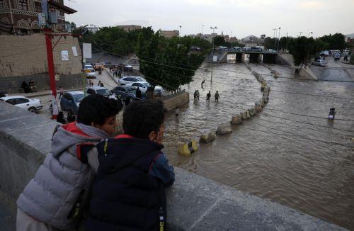 epa12929032 People stand on an overpass as floodwater flows through a street below following torrential rainfall in Sana'a, Yemen, 02 May 2026. Yemen's National Center of Meteorology and Early Warning has warned of further heavy rains and possible flooding across much of the country.  EPA/YAHYA ARHAB