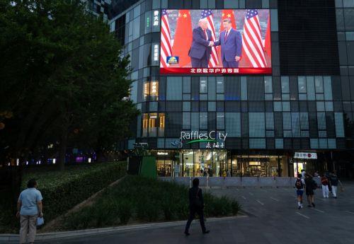 epa12957041 People walk in front of a TV screen broadcasting the summit between US President Donald Trump (L) and Chinese President Xi Jinping, in Beijing, China, 14 May 2026. US President Trump is in Beijing for a high-stakes state visit running through 15 May, marking his first return to the mainland since 2017.  EPA/JESSICA LEE