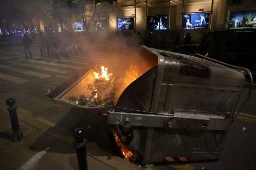 epa12988491 An overturned dumpster burns as riot police officers take positions after a mass student-led anti-government rally in Belgrade, Serbia, 23 May 2026. Thousands gathered to ramp up pressure on the government and demand early parliamentary elections. The political movement originally erupted across the country following the November 2024 canopy...