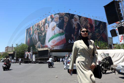 epa12992441 A woman walks next to a huge billboard in a street in Tehran, Iran, 25 May 2026. The US and Iran voiced optimism regarding a potential peace agreement and the reopening of the Strait of Hormuz, though both sides emphasized that no such deal has been reached yet.  EPA/ABEDIN TAHERKENAREH