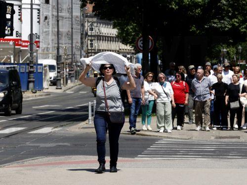epa12992653 A woman holds a scarf over her head to protect herself from the sun in downtown Zagreb, Croatia, 25 May 2026. Reports state that in recent days Croatia and Zagreb have recorded unusually high temperatures for this time of year, exceeding 30 degrees Celsius. Europe is bracing for a heatwave, as forecasters predict temperatures are expected to...
