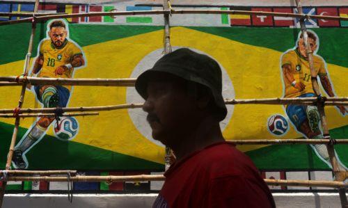 epa13032253 An Indian man walks near a street mural of Brazil's players and national flag in Kolkata, india, 12 June 2026. The FIFA World Cup 2026 runs from 11 June to 19 July 2026.  EPA/PIYAL ADHIKARY
