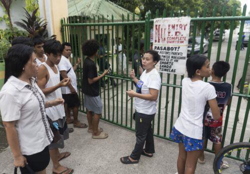 epa13056475 People wait outside the gates of the San Jose National High School in Tacloban City, Leyte province, Philippines, 22 June 2026. According to the Tacloban City Police Office (TCPO), three students were killed and more than five others were injured and taken to medical facilities for treatment. TCPO said the two suspects have been taken into...