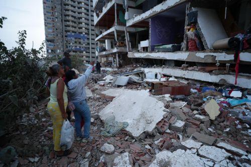 epa13063444 Residents look at a building damaged during the twin 7.2 and 7.5-magnitude earthquakes that struck the country, in Catia la Mar, Venezuela, 25 June 2026. At least 32 people were killed and 700 were injured after two back-to-back earthquakes hit north-central Venezuela in rapid succession, triggering the collapse of buildings, cracking facades,...