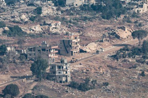 epa13070682 Israeli construction equipment passes by an Israeli flag waving atop a destroyed house in the southern Lebanese village of Taybeh, as seen from the Israeli side of the border in the Upper Galilee, northern Israel, 28 June 2026, amid an Israel-Lebanon ceasefire.  EPA/ATEF SAFADI