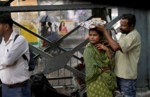 epa13072414 An Indian family waits under a footbridge during heavy rain in Kolkata, India, 29 June 2026. The India Meteorological Department (IMD) issued a red alert for thunderstorms with lightning and heavy rainfall, disrupting daily life across parts of West Bengal for the past several days.  EPA/PIYAL ADHIKARY