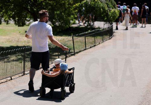 epa13098185 A father trollies his children through St.James's Park in London, Britain, 08 July 2026. Amber and yellow heat-health alerts are in place across England as the UK braces for one of the longest-lasting heatwaves for fifty years. Temperatures may rise as high as 35 degrees Celsius for parts of southern England this week.  EPA/ANDY RAIN