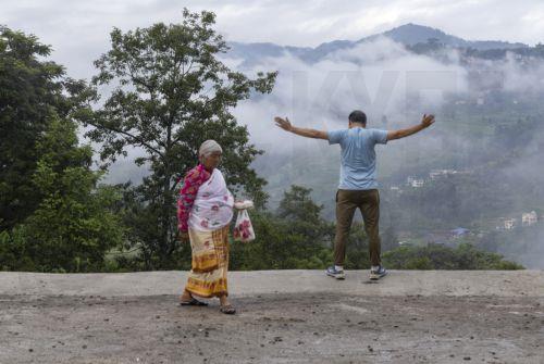 epa13124221 An elderly woman walks past a person exercising in Bungamati on the outskirts of Kathmandu, Nepal, 21 July 2026. Nepal's Meteorological Forecasting Division has announced that the monsoon season has officially begun across the country.  EPA/NARENDRA SHRESTHA