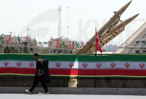 epa13129785 A person with a musical instrument walks next to Iranian missiles, Zolfaghar, on display at Azadi Square in Tehran, Iran, 24 July 2026. Conflict between Iran and the US over the Strait of Hormuz continues, as US strikes have targeted several locations across Iran.  EPA/ABEDIN TAHERKENAREH RESTRICTIONS: NO Access Israel Media/Persian Language TV...
