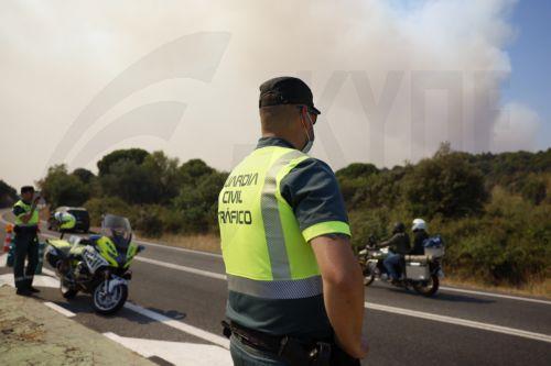 epa13129833 Civil Guard officers control access to towns near the fire on M-512 road in Navas del Rey, Madrid, Spain, 24 July 2026. Commanders of the operation against the forest fire affecting the southwest of the Autonomous Community of Madrid ordered the evacuation of the municipalities of Chapinería, Navas del Rey, and Colmenar del Arroyo on 24 July, as...