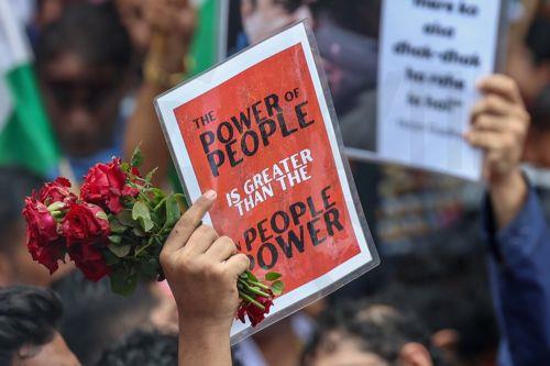 epa13133542 A protester holds a placard as supporters of the youth-led satirical political movement Cockroach Janta Party (CJP) celebrate the resignation of Union Education Minister Dharmendra Pradhan, in Mumbai, India, 26 July 2026. Pradhan tendered his resignation on 25 July following nationwide student protests over examination paper leaks. ...