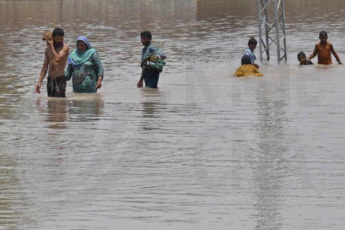 epa13135842 People wade through a flooded area after heavy monsoon rains raised the water level of the Ravi River in Muridke, Pakistan, 27 July 2026. Authorities established 17 flood relief camps across Lahore Division, mainly in Nankana Sahib and Sheikhupura, and introduced an AI-based dashboard to monitor reservoir conditions and support flood...