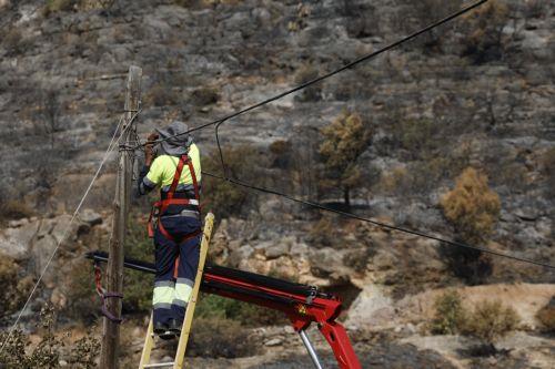 epa13141257 A worker is repairing the power grid following a wildfire in Carbonaire at La Vall d'Uixo, Castellon, Spain, 30 July 2026. The fire, which was declared on 25 July 2026, is still not under control and has already burned 9,300 hectares, with a perimeter of 84 kilometers.  EPA/KAI FOERSTERLING
