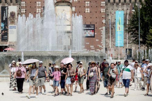 epa13143864 People use fans and shelter from the sun under umbrellas on a hot summer day in Milan, Italy, 31 July 2026. The Italian Ministry of Health issued a 'red-dot' heatwave alert for 19 cities starting 01 August. By 02 August, the number of cities under red alert is expected to increase to 23 out of the 27 being monitored.  EPA/MOURAD BALTI TOUATI