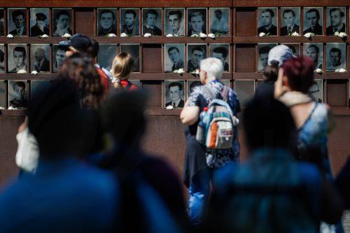 epa13166442 Visitors look at portraits of victims of the Berlin Wall that are part of an installation, decorated with flowers, at the Berlin Wall Memorial after the 65th anniversary commemoration of the construction of the Berlin Wall in Berlin, Germany, 13 August 2026. Some 65 years ago, on 13 August 1961, the Berlin Wall construction started.  EPA/CLEMENS...