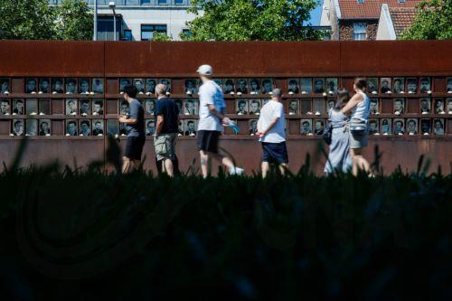epa13166446 Visitors look at portraits of victims of the Berlin Wall that are part of an installation, decorated with flowers, at the Berlin Wall Memorial after the 65th anniversary commemoration of the construction of the Berlin Wall in Berlin, Germany, 13 August 2026. Some 65 years ago, on 13 August 1961, the Berlin Wall construction started.  EPA/CLEMENS...