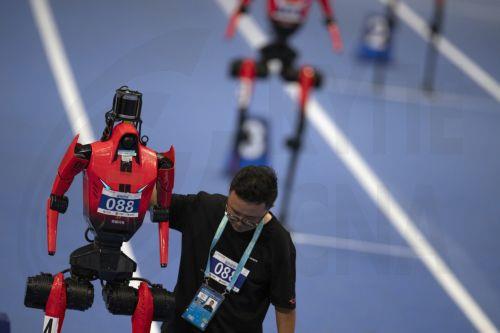 epa13186088 A team member sets a humanoid robot for the large robots 400m event during the 2026 World Humanoid Robot Games at the National Speed Skating Oval in Beijing, China, 23 August, 2026. The 2026 World Humanoid Robot Games are being held in Beijing until 26 August.  EPA/ANDRES MARTINEZ CASARES