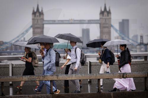 epaselect epa13194053 Commuters holding umbrellas cross London Bridge during heavy rainfall in London, Britain, 27 August 2026. The heavy rain forecast comes as 71 percent of England and all of Wales remain officially in drought, even as the Met Office issues thunderstorm warnings across the country with up to a month’s worth of rain potentially falling on...