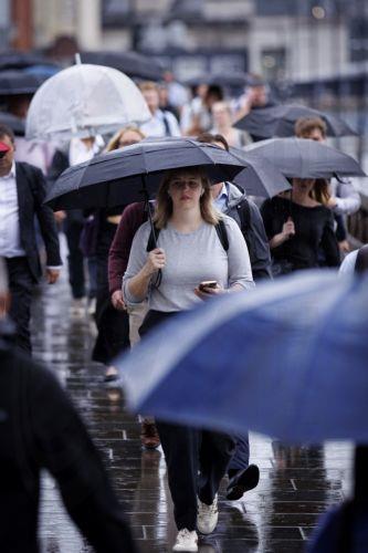 epa13194106 Commuters holding umbrellas cross London Bridge during heavy rainfall in London, Britain, 27 August 2026. The heavy rain forecast comes as 71 percent of England and all of Wales remain officially in drought, even as the Met Office issues thunderstorm warnings across the country with up to a month’s worth of rain potentially falling on parched...