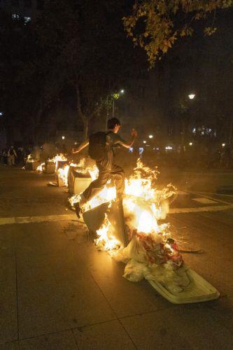 epa13283827 A protestor jumps over trash cans on fire during a protest for the right to housing in Barcelona, Spain, 05 October 2026. Protesters took to the streets in Barcelona to demand measures to address the housing crisis and rising housing costs.  EPA/MARTA PEREZ