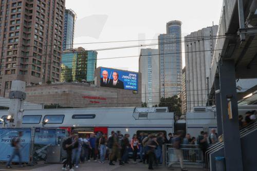epa13283973 A large election billboard (top) shows Israeli Prime Minister Benjamin Netanyahu (C-L) and leader of the Yashar party, Gadi Eisenkot (C-R), with a message in Hebrew stating 'Netanyahu, come to a debate; what are you afraid of?' in Tel Aviv, Israel, 06 October 2026. Israel will hold elections on 27 October.  EPA/ABIR SULTAN EPA