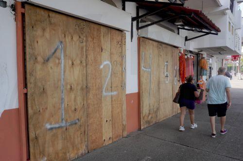 epa13293002 Tourists stroll through a store with its doors and windows boarded up in anticipation of Hurricane Simon, which reached Category 2 status in the Mexican Pacific with sustained winds of 155 kilometers per hour, in Puerto Vallarta, Mexico, 09 October 2026.  EPA/Arturo Montero