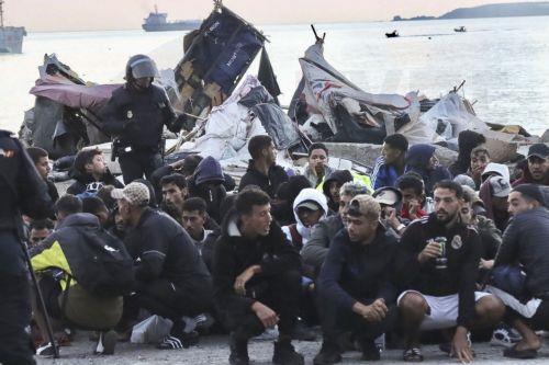 epa13295936 Spanish National Police officers stand next to migrants as they clear a migrant camp set up in the esplanade in front of the old El Guano factory in Ceuta, Spain, 11 October 2026. Police carried out the new operation just over 48 hours before an official visit by the Spanish royal couple to the Spanish enclave in North Africa.  EPA/Reduan BEST...