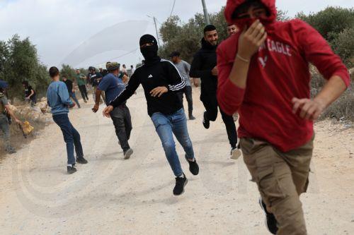epa13309134 Palestinians run for cover from tear gas fired by the Israeli army following a settlers' attack on families harvesting their olive trees in Abu Falah, West Bank, 16 October 2026. According to Wafa, several Palestinians and a foreign journalist were injured in Israeli settler attacks on residents and olive pickers up to 3 locations in the central...