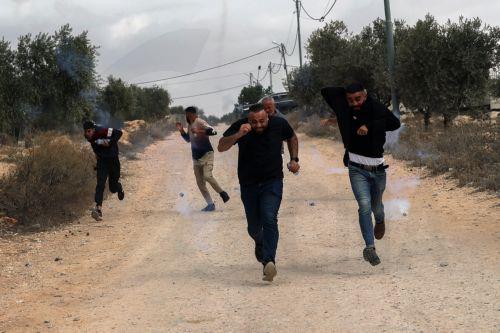epa13309135 Palestinians run for cover from tear gas fired by the Israeli army following a settlers' attack on families harvesting their olive trees in Abu Falah, West Bank, 16 October 2026. According to Wafa, several Palestinians and a foreign journalist were injured in Israeli settler attacks on residents and olive pickers up to 3 locations in the central...