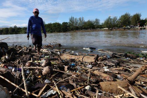epa13333726 A man walks past a pile of plastic and wooden waste covering a riverbank in Banda Aceh, Indonesia, 27 October 2026. Plastic waste washed down from residential areas via local rivers accumulates along coastal banks before flowing into the sea.  EPA/HOTLI SIMANJUNTAK