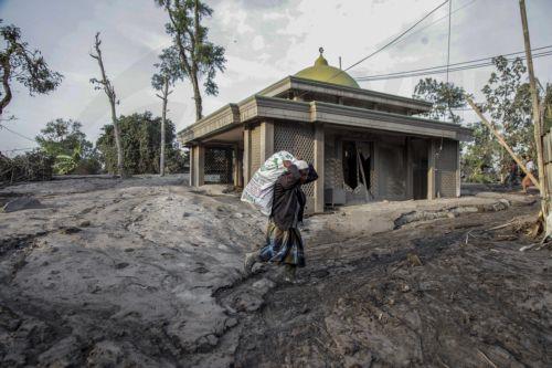 epa10349040 A villager carries his belongings out of his village affected by the volcanic ash from the eruption of Mount Semeru at Kajar Kuning village in Lumajang, East Java, Indonesia, 05 December 2022. Authorities has raised Mount Semeru alert status to the highest level following its eruption early on 04 December 2022 forcing around two thousands...